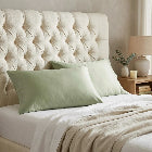 Sage bamboo lyocell pillowcase styled on a bed with tufted headboard — bedroom lifestyle setting.